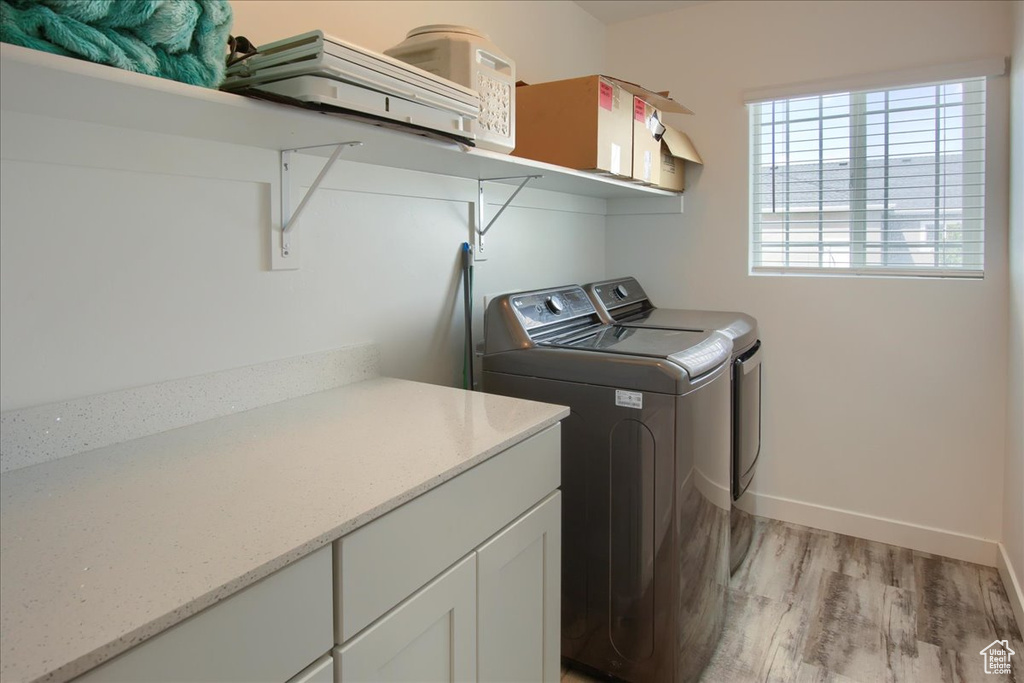 Washroom with independent washer and dryer, light wood-style flooring, and baseboards