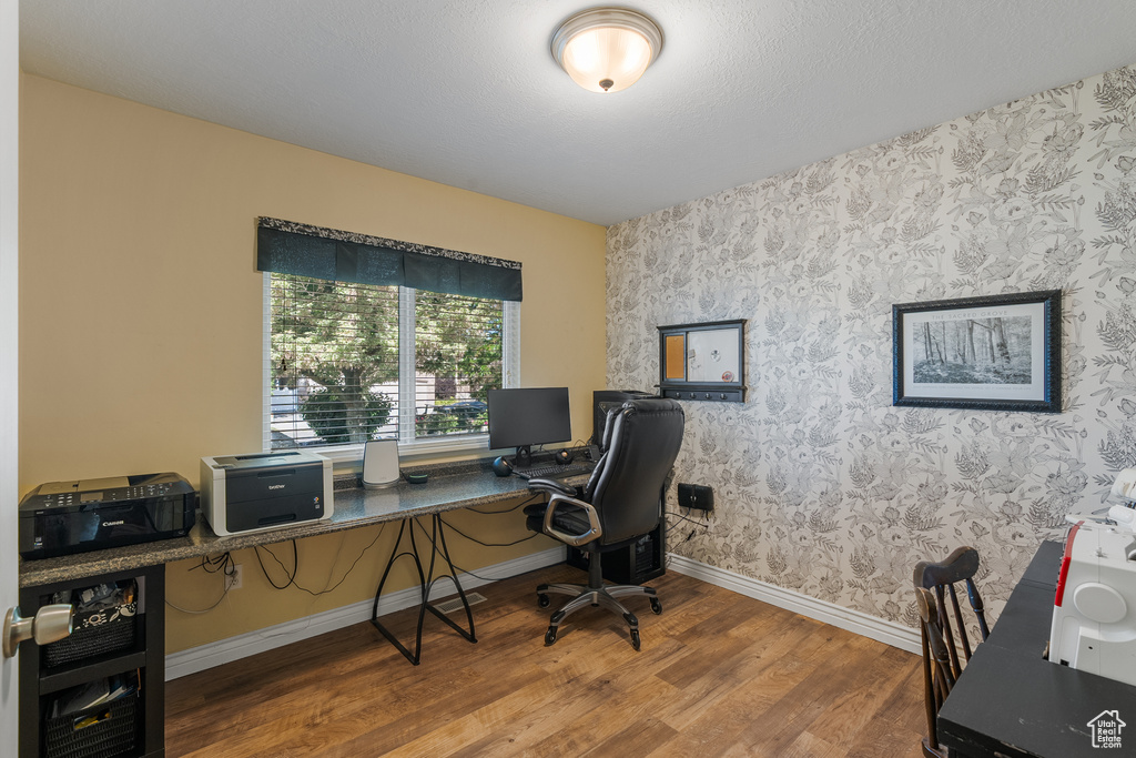 Office featuring wallpapered walls, wood finished floors, and baseboards