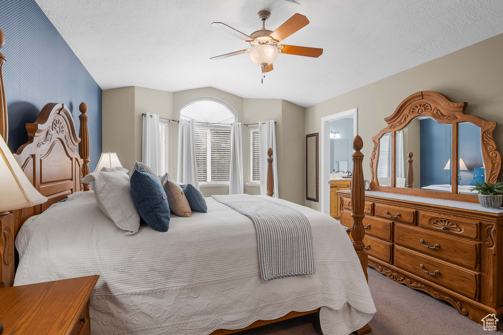 Bedroom featuring carpet, vaulted ceiling, a ceiling fan, and ensuite bath