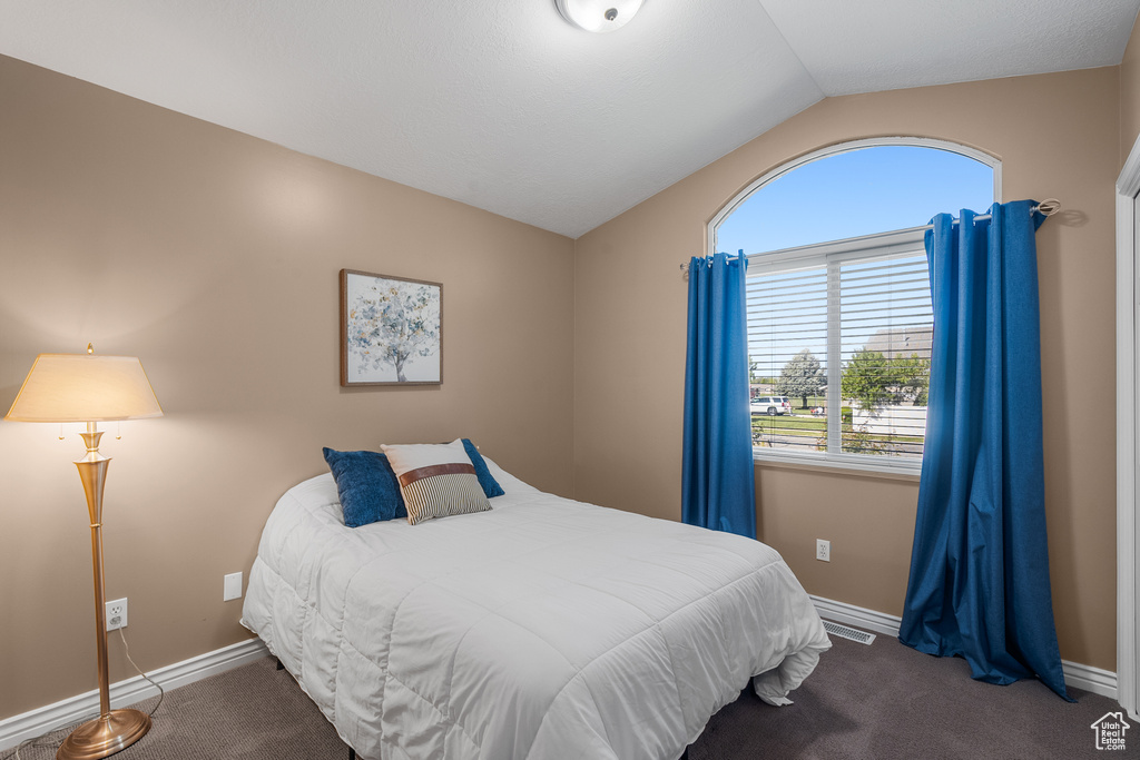 Carpeted bedroom featuring vaulted ceiling and baseboards