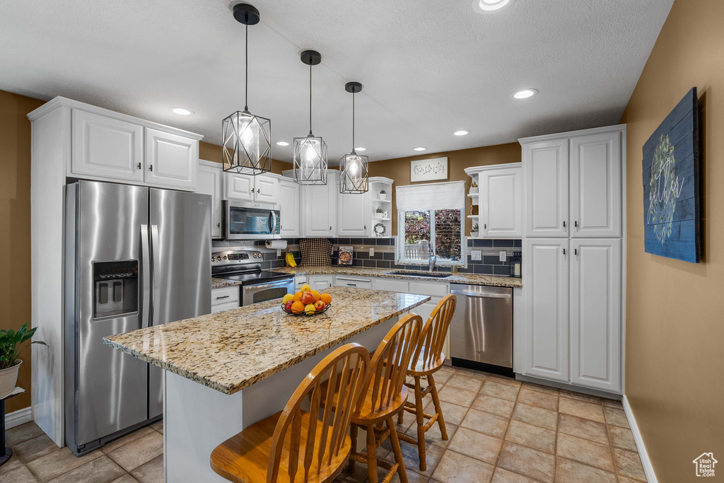 Kitchen with appliances with stainless steel finishes, open shelves, white cabinetry, backsplash, and recessed lighting
