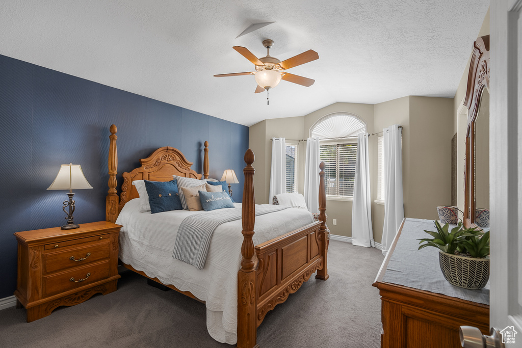 Carpeted bedroom with vaulted ceiling, baseboards, and a ceiling fan