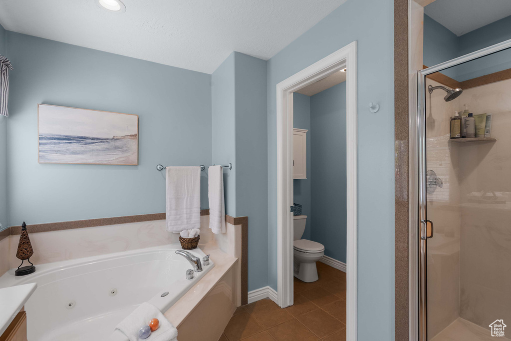 Bathroom with a stall shower, a whirlpool tub, toilet, tile patterned flooring, and vanity
