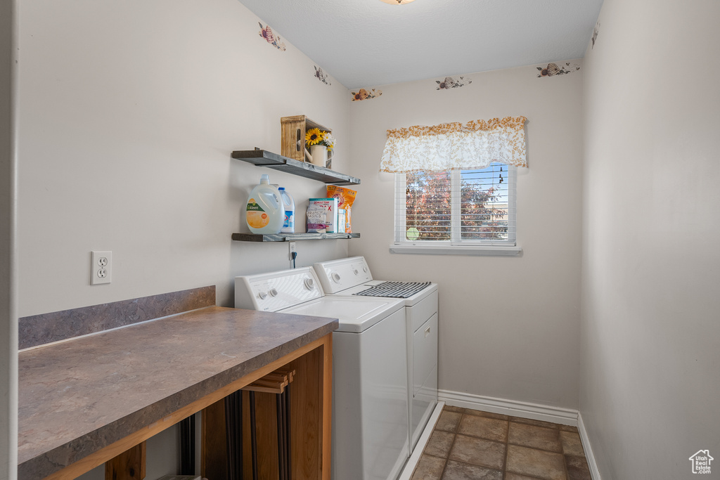 Laundry room featuring washer and clothes dryer, baseboards, and stone finish floors