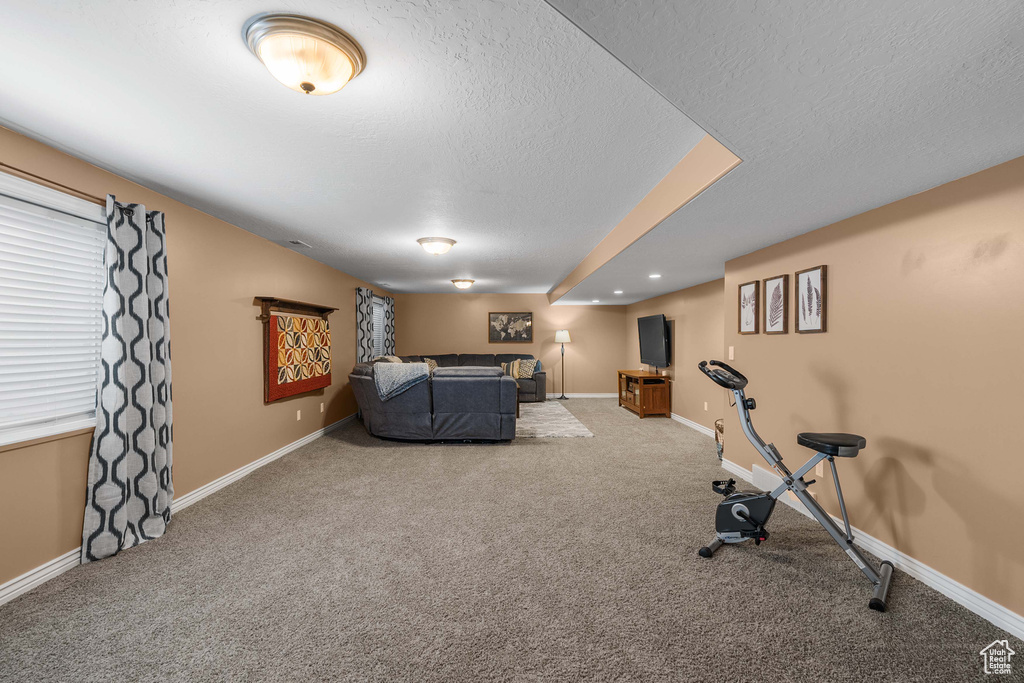 Carpeted living area featuring a textured ceiling and baseboards