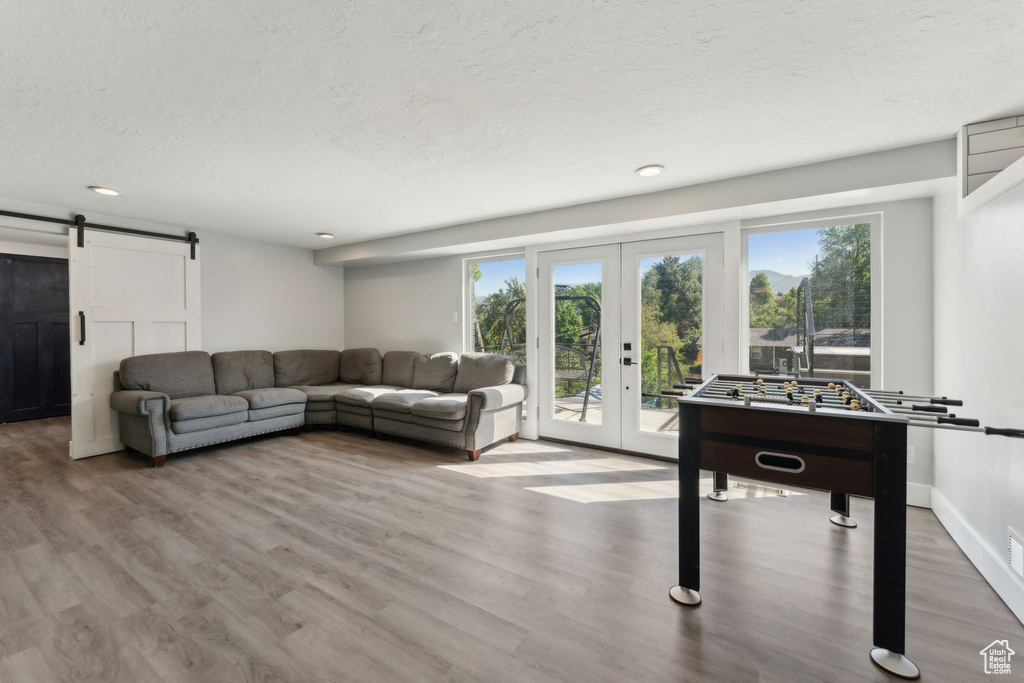 Living area featuring a barn door, french doors, wood finished floors, a textured ceiling, and recessed lighting