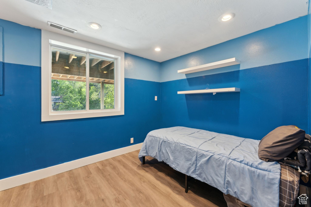 Bedroom with wood finished floors, baseboards, and recessed lighting