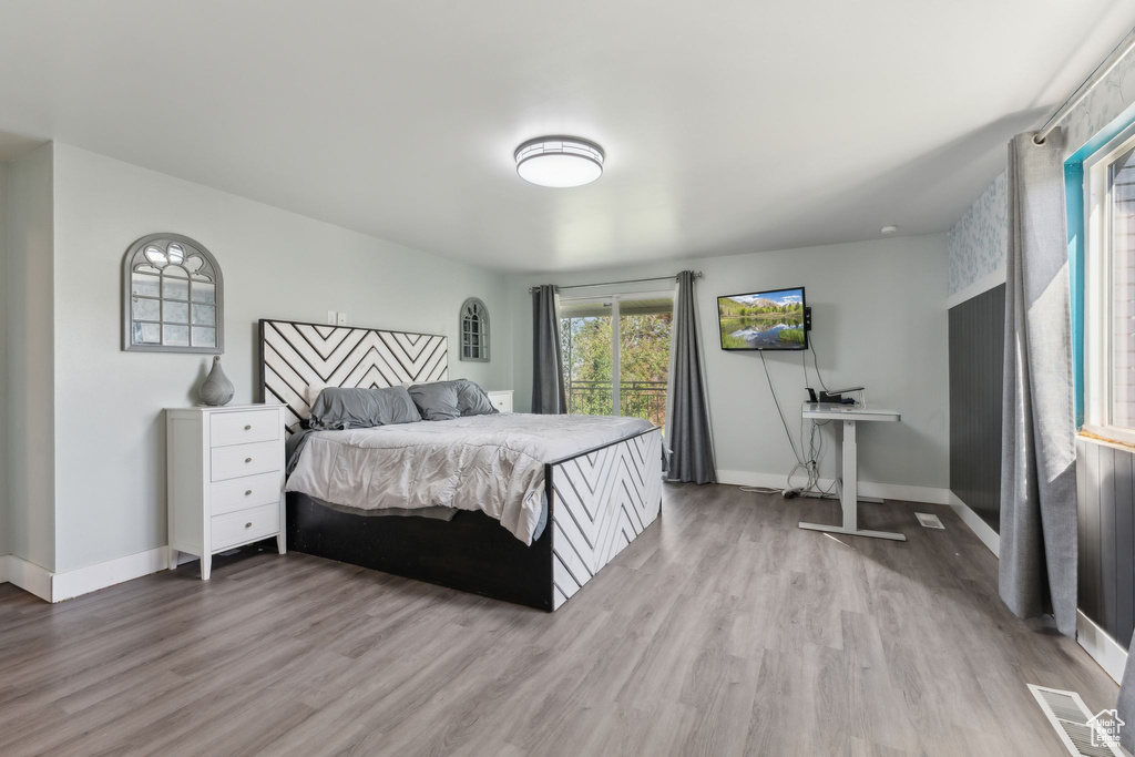 Bedroom with wood finished floors, multiple windows, and baseboards