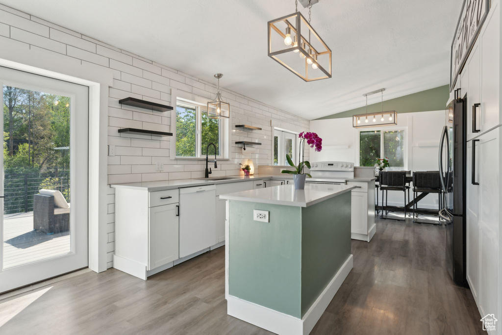 Kitchen featuring white appliances, a sink, open shelves, vaulted ceiling, and a center island