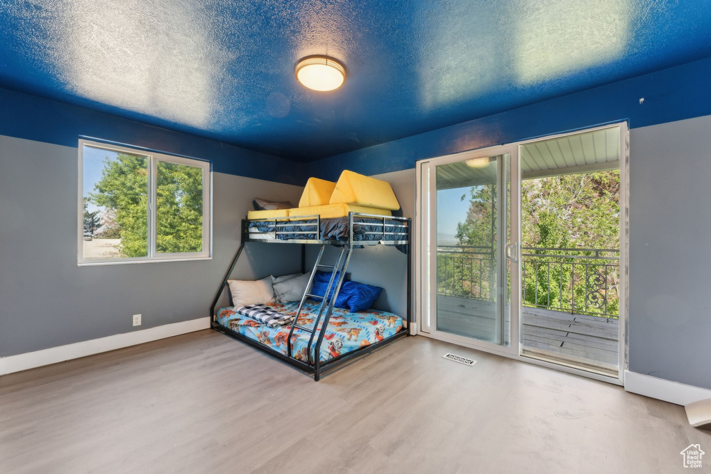 Bedroom featuring access to exterior, multiple windows, wood finished floors, baseboards, and a textured ceiling