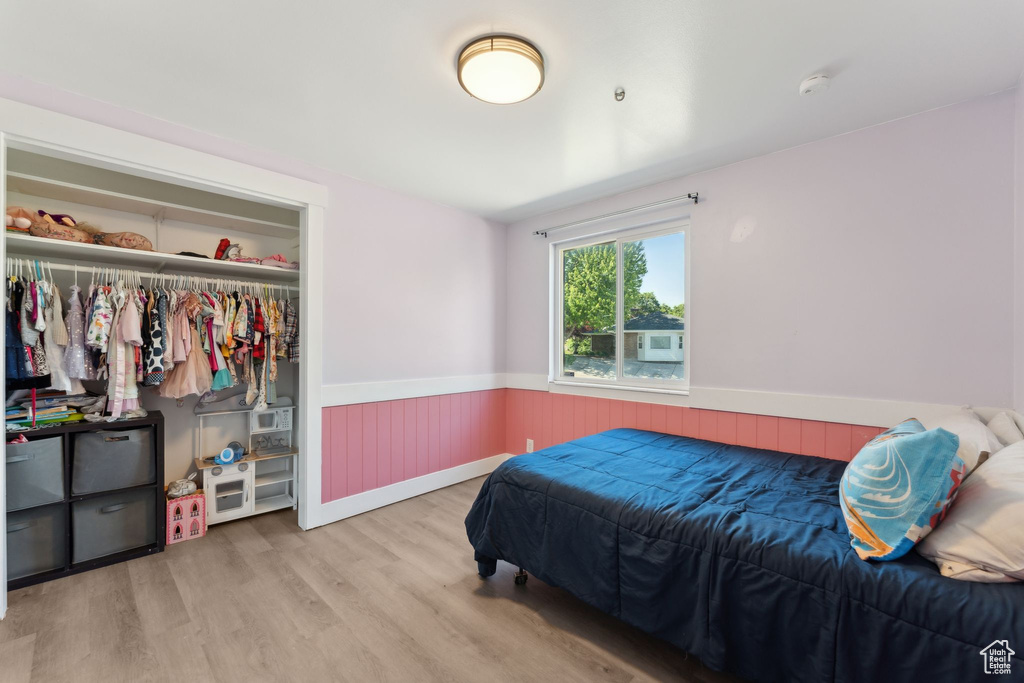 Bedroom featuring a wainscoted wall, wood finished floors, and a closet