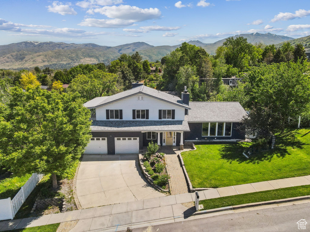 View of front of property featuring concrete driveway, a garage, a mountain view, and a chimney