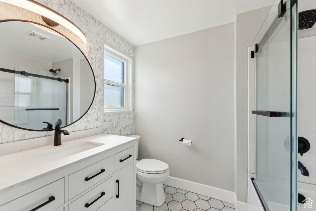 Bathroom with vanity, toilet, tile patterned flooring, and enclosed tub / shower combo