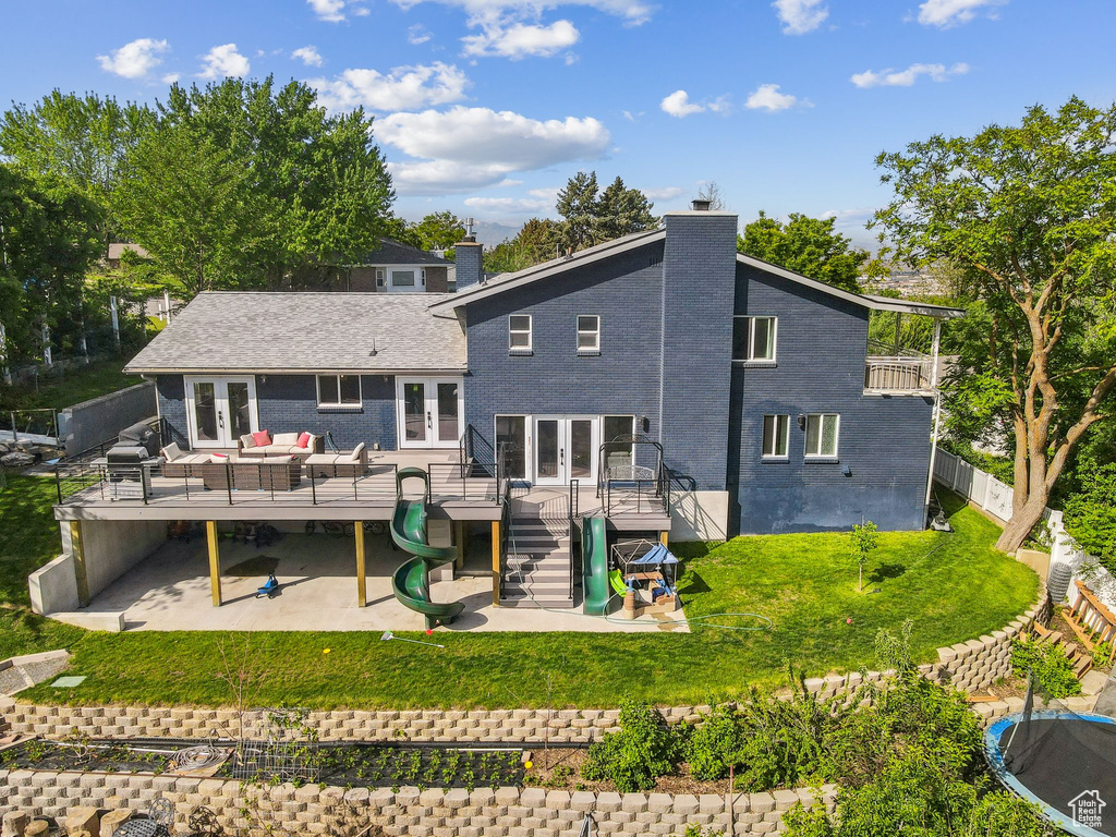 Rear view of house with french doors, a wooden deck, a patio, a chimney, and outdoor lounge area