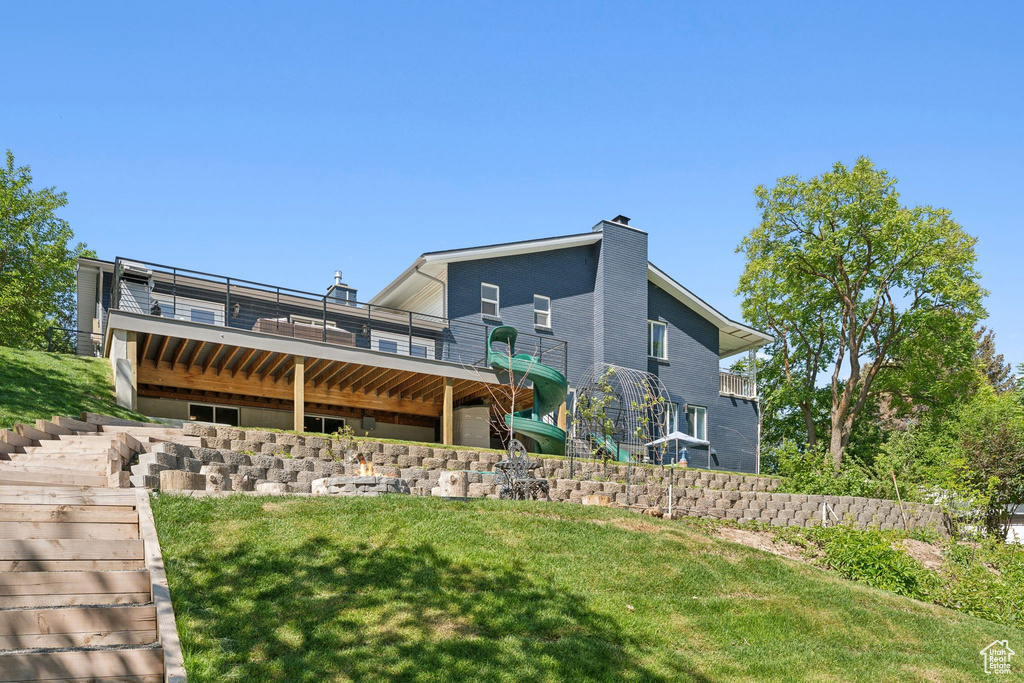 Back of property featuring a chimney, a yard, stairway, a wooden deck, and brick siding