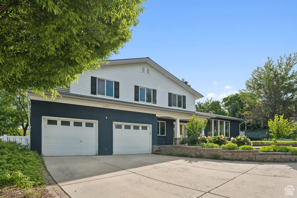 View of front of property with driveway, an attached garage, and brick siding