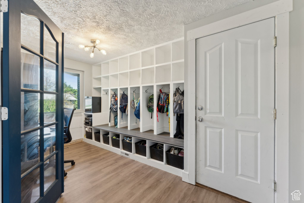Mudroom featuring a chandelier, wood finished floors, and a textured ceiling