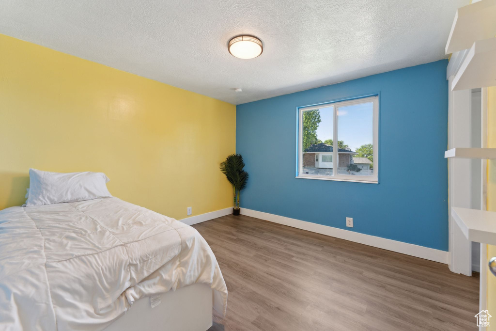 Bedroom featuring a textured ceiling, wood finished floors, and baseboards