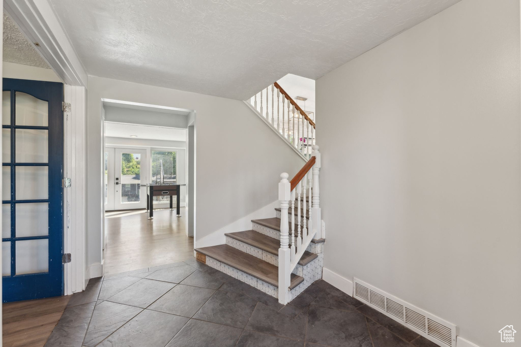 Stairway with a textured ceiling, baseboards, and french doors