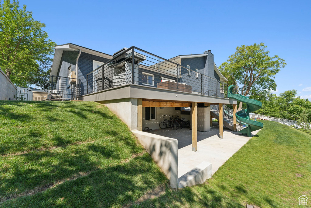 Back of house with a patio, a playground, a lawn, and stucco siding