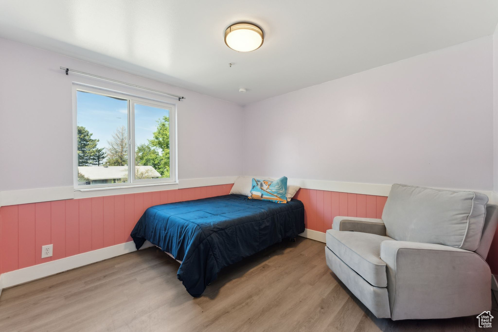 Bedroom with wainscoting and light wood-type flooring