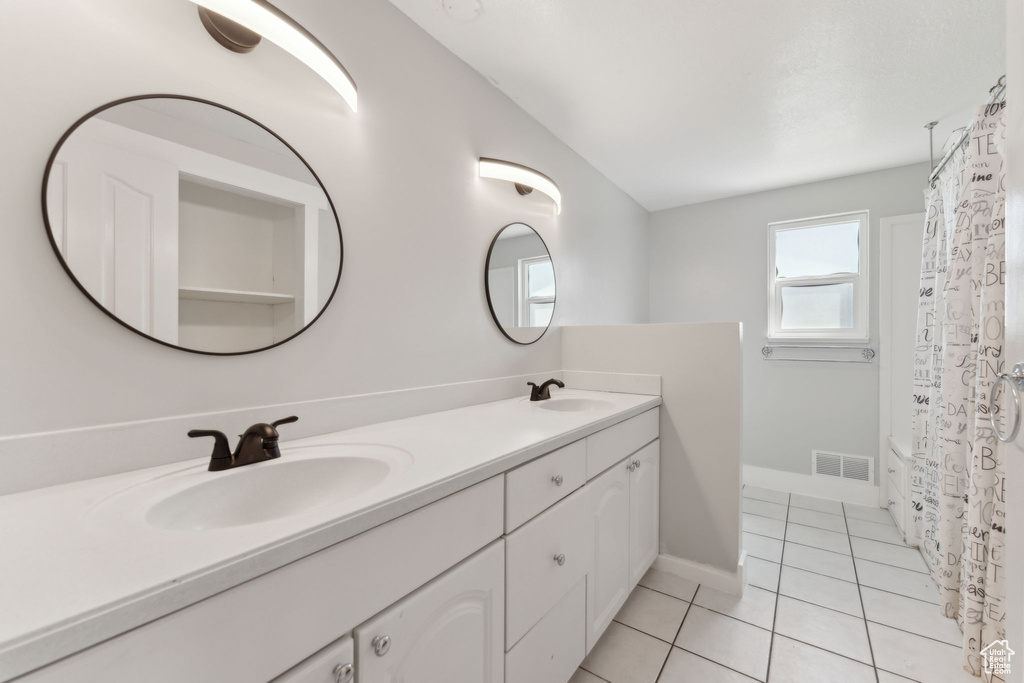 Full bathroom with double vanity, tile patterned flooring, and baseboards