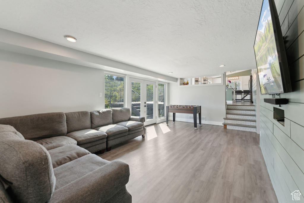 Living room with wood finished floors, french doors, stairs, a textured ceiling, and baseboards