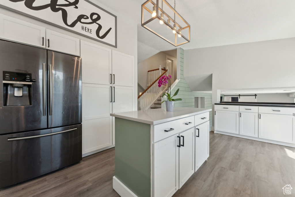 Kitchen with stainless steel fridge, light wood-style floors, and white cabinets