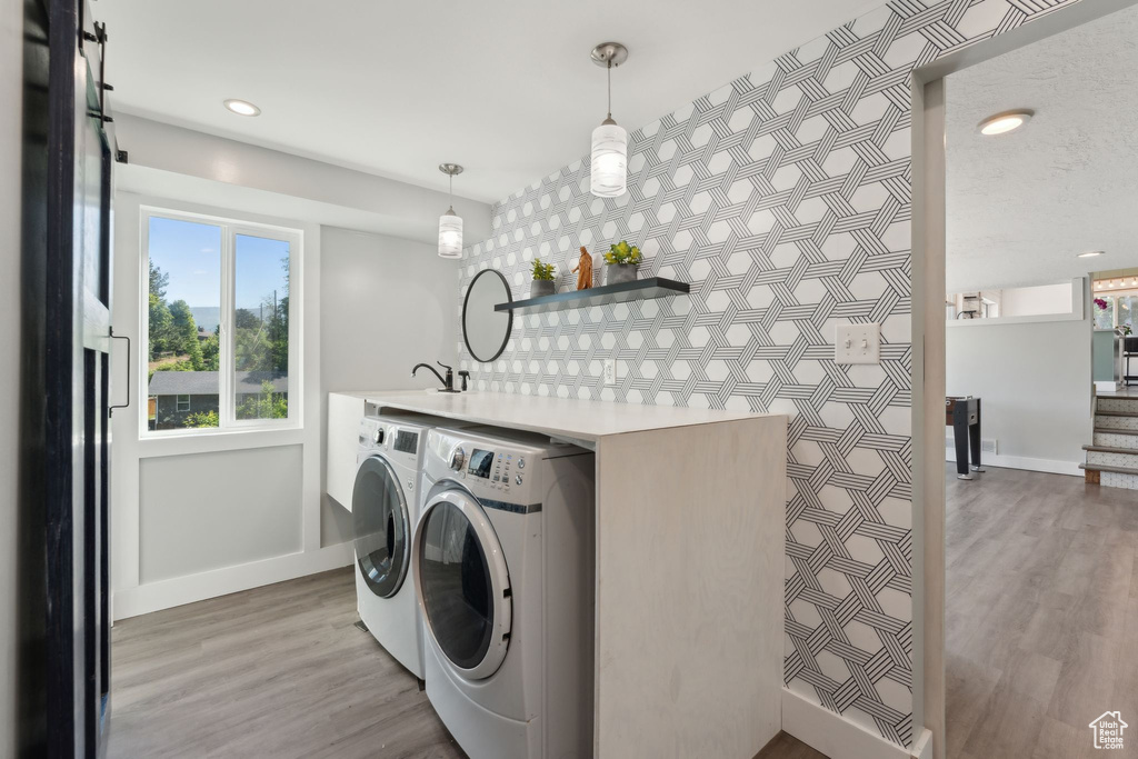 Laundry area featuring separate washer and dryer, baseboards, light wood-type flooring, recessed lighting, and an accent wall