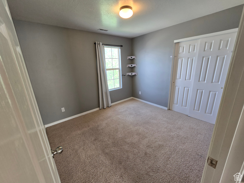 Unfurnished bedroom featuring carpet floors, baseboards, and a closet