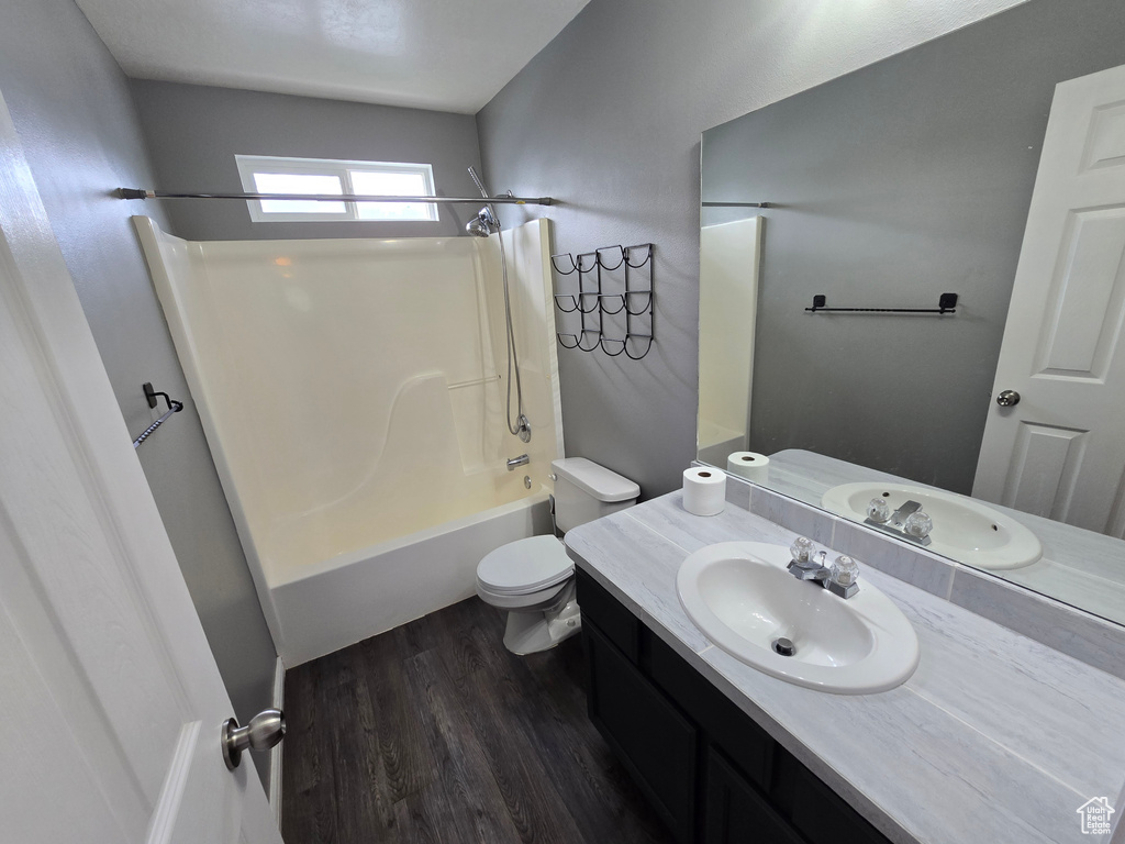 Bathroom with toilet, wood finished floors, vanity, and shower / tub combination