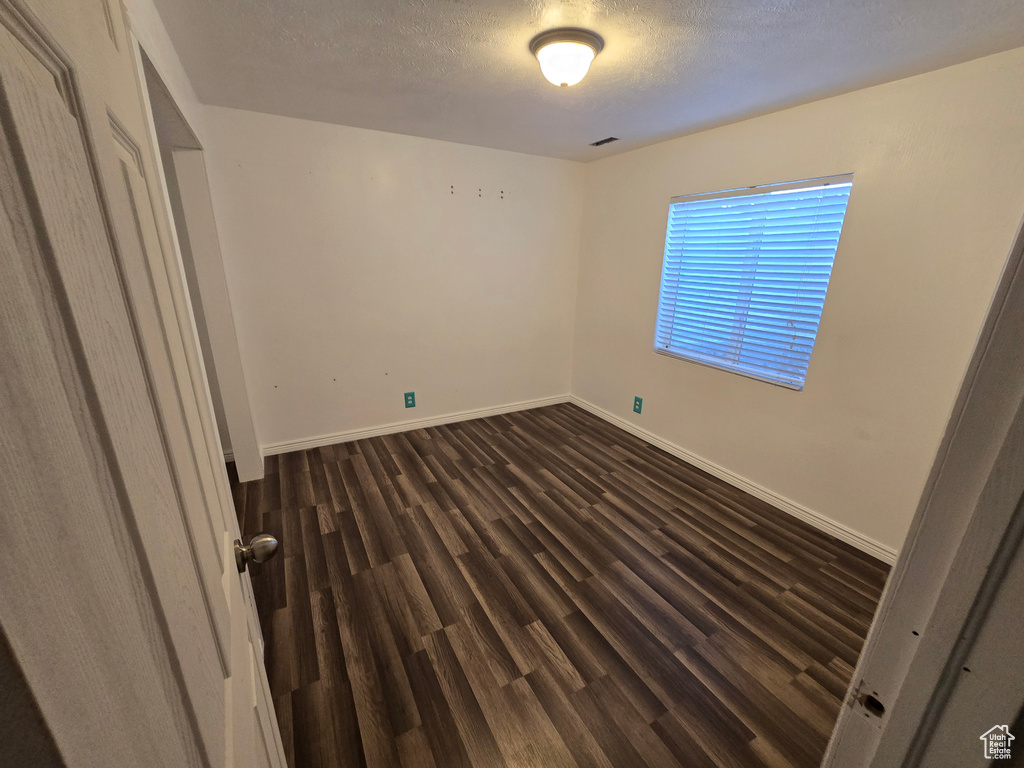 Unfurnished bedroom with dark wood finished floors, baseboards, and a textured ceiling