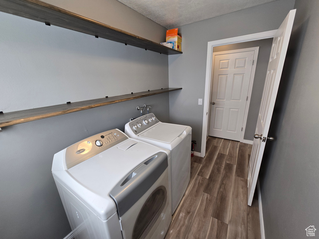 Washroom featuring separate washer and dryer, dark wood-style floors, and baseboards