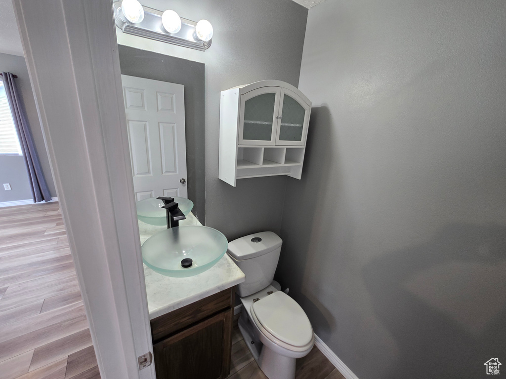 Bathroom featuring vanity, wood finished floors, toilet, and baseboards