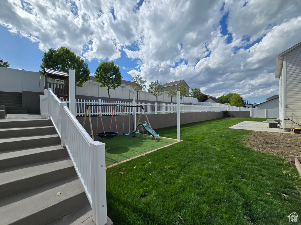View of yard with stairway, a playground, and central AC unit
