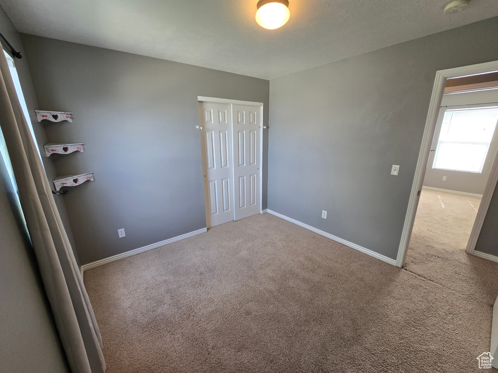 Unfurnished bedroom with carpet floors, baseboards, and a closet