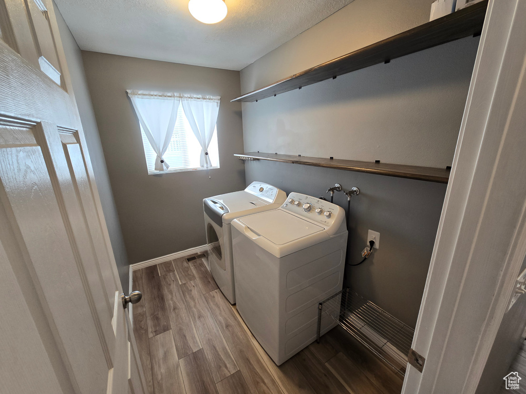 Washroom with washer and dryer, wood finished floors, and baseboards