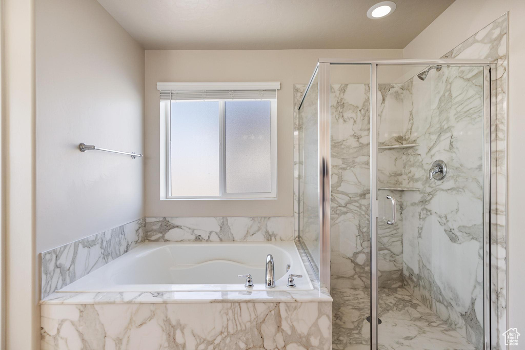 Bathroom featuring a bath and a marble finish shower