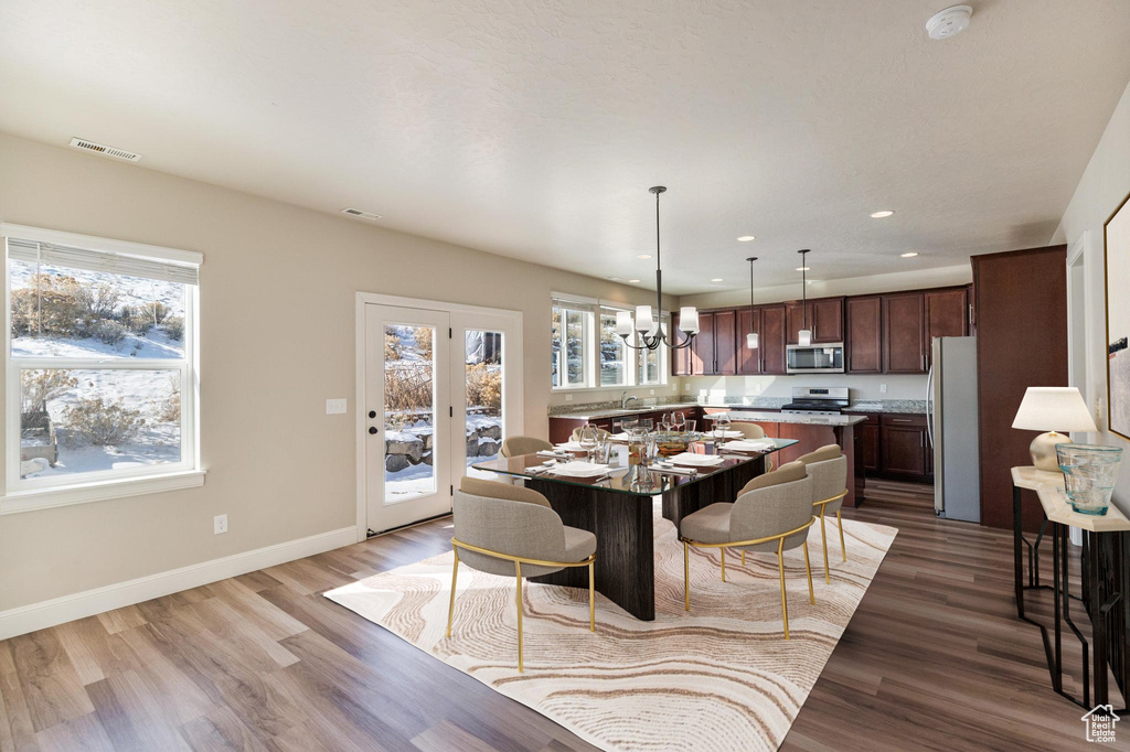 Dining space featuring plenty of natural light, wood finished floors, a chandelier, baseboards, and recessed lighting
