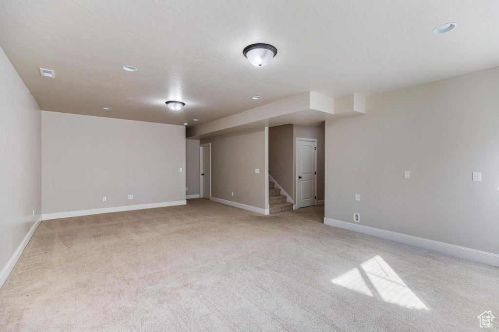 Unfurnished room featuring light carpet, stairs, baseboards, recessed lighting, and a textured ceiling