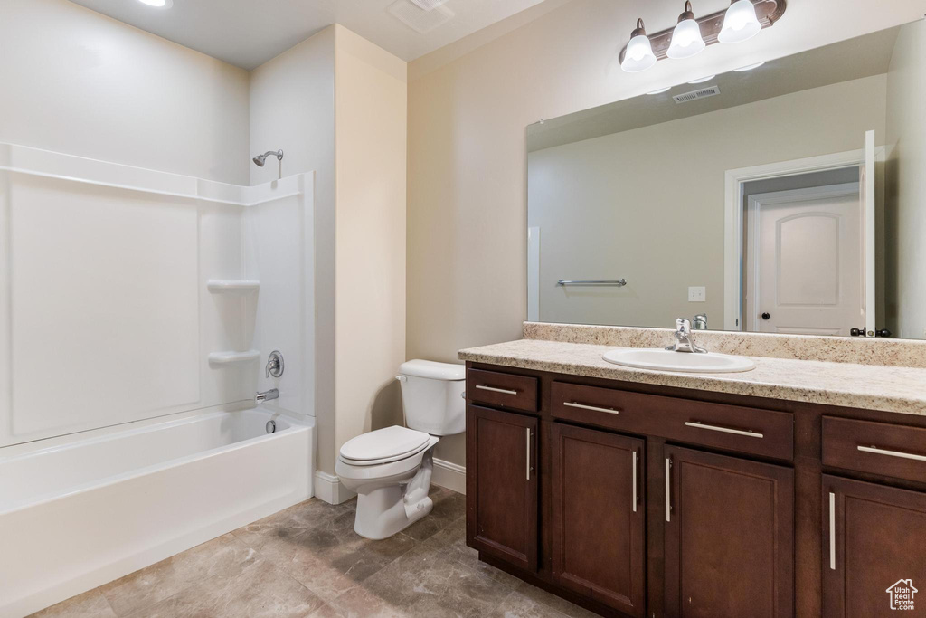Bathroom featuring vanity, toilet, shower / tub combination, and baseboards