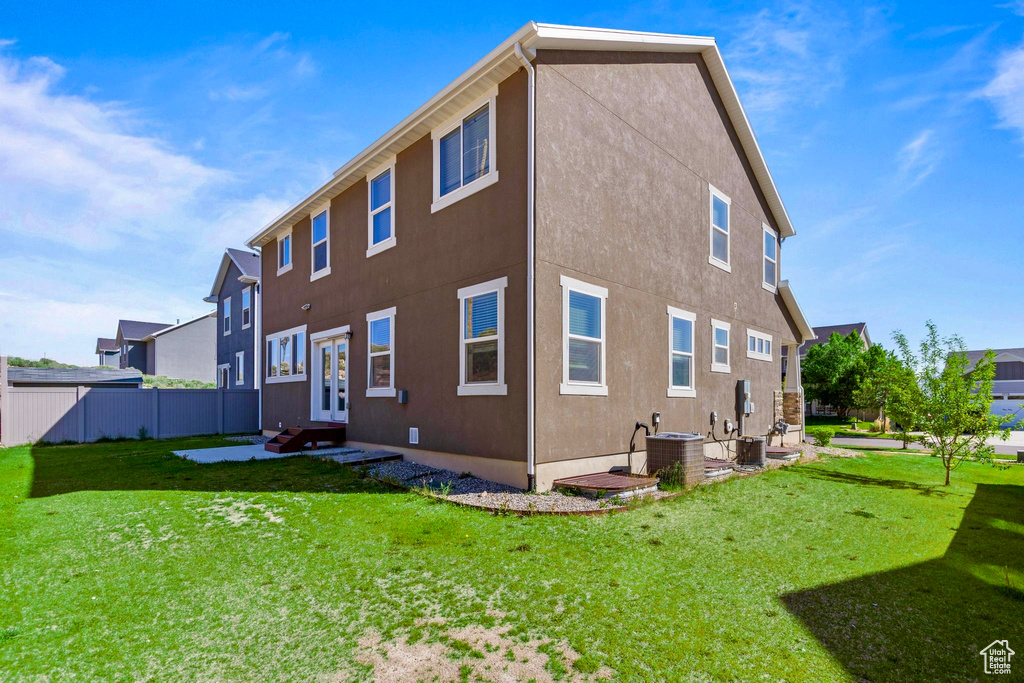 Rear view of house with central AC, french doors, stucco siding, and entry steps