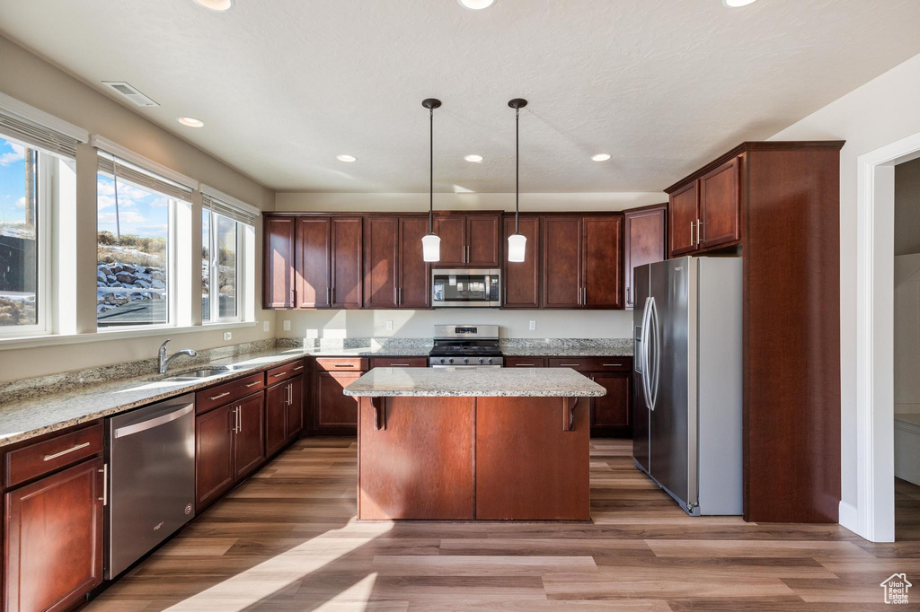 Kitchen featuring stainless steel appliances, a sink, a kitchen island, recessed lighting, and light stone counters