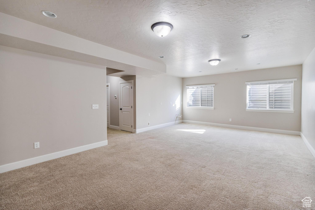 Spare room featuring light colored carpet, baseboards, and a textured ceiling