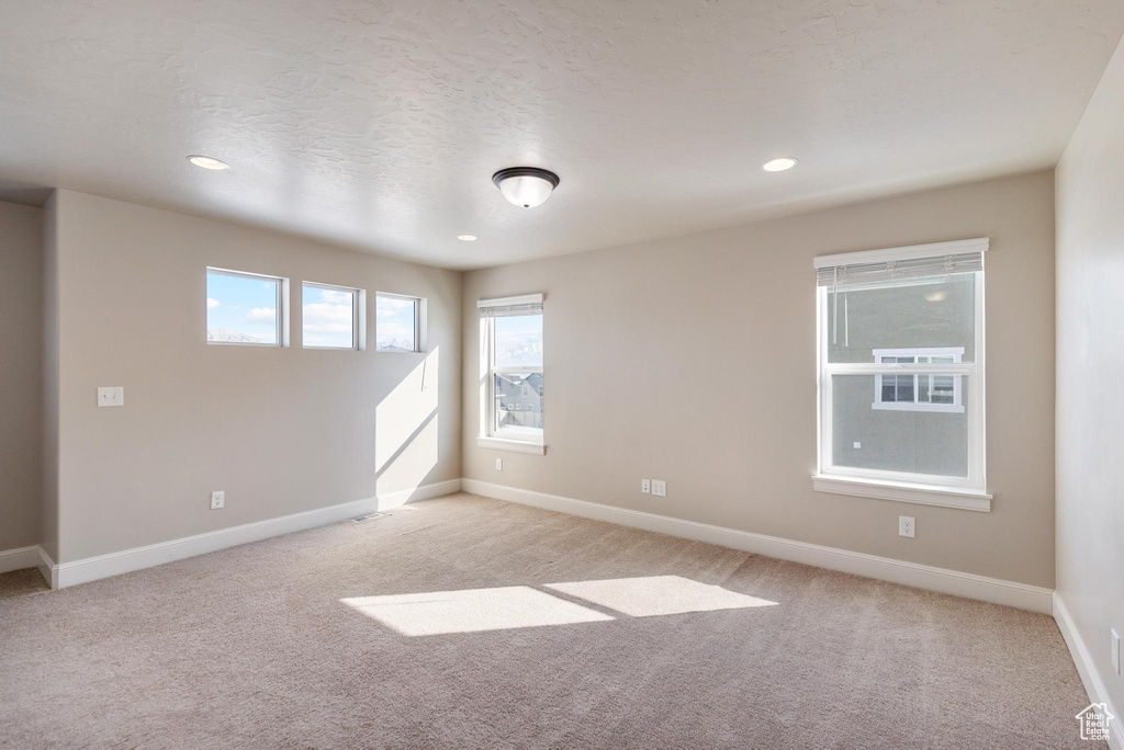 Empty room featuring light colored carpet, baseboards, and recessed lighting