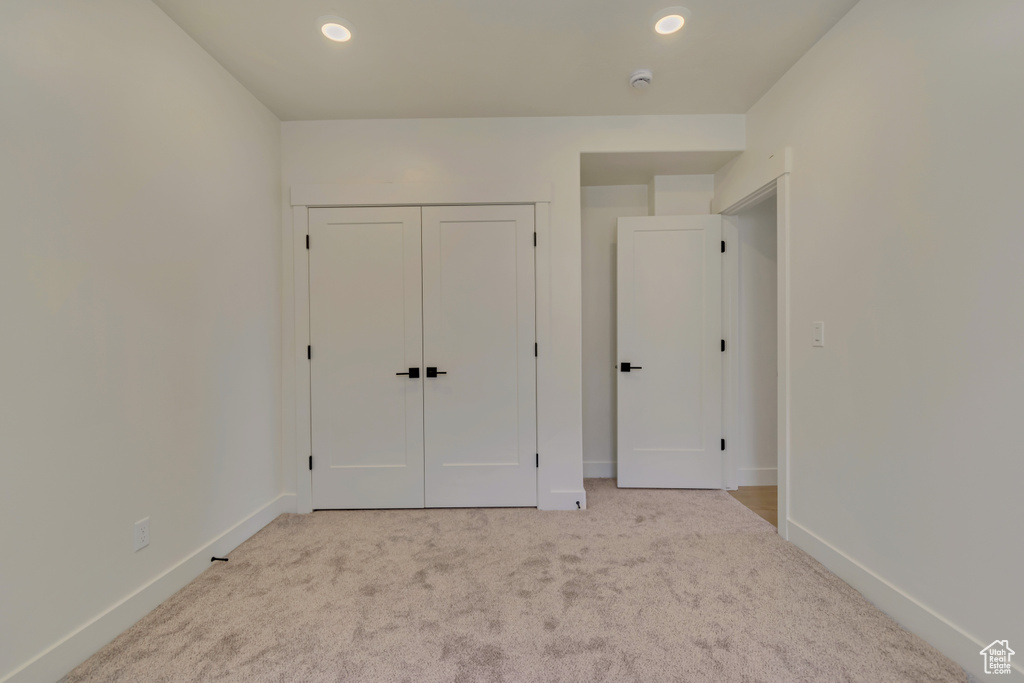 Unfurnished bedroom featuring light carpet, baseboards, recessed lighting, and a closet