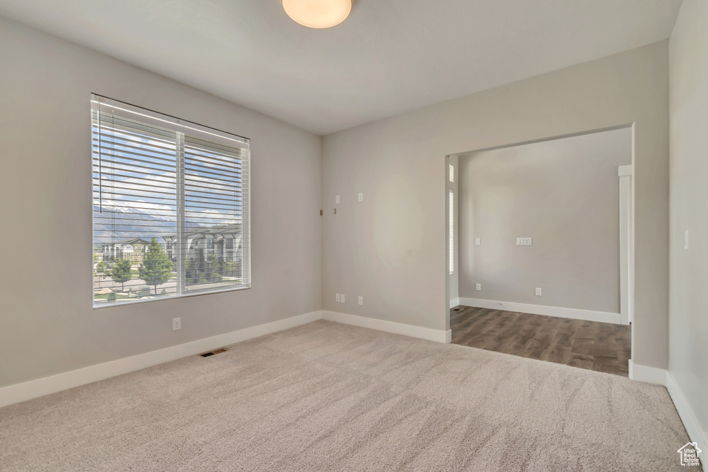 Carpeted spare room featuring baseboards