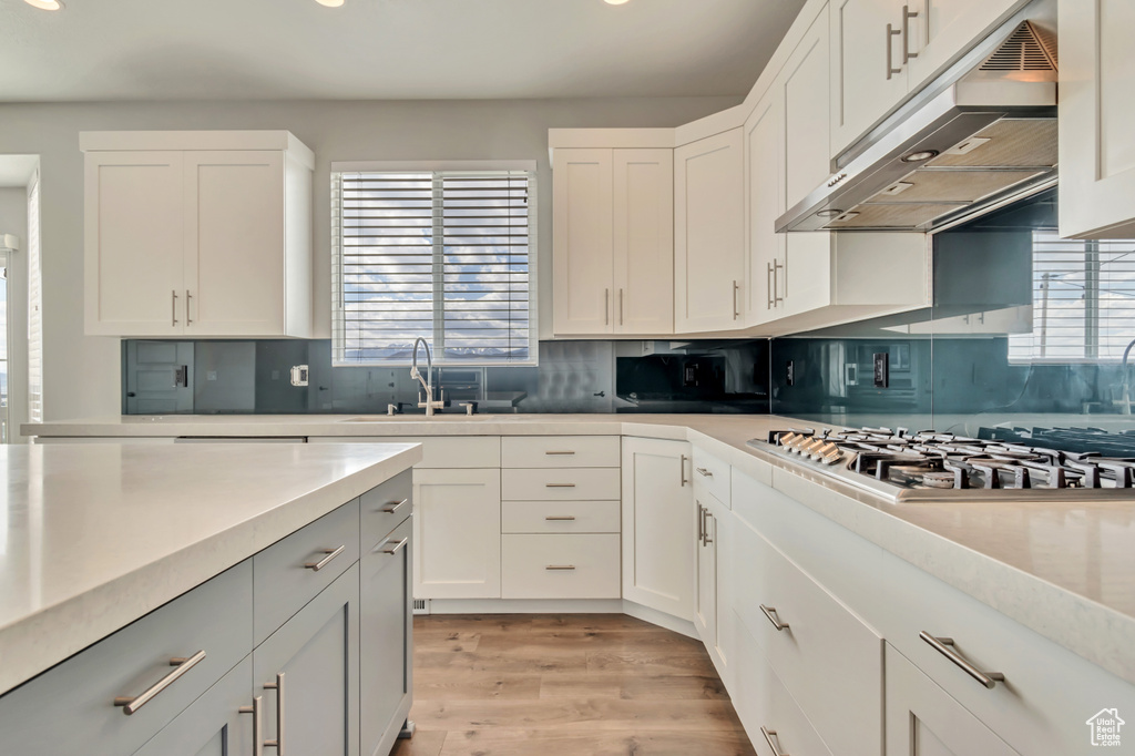 Kitchen with under cabinet range hood, stainless steel gas stovetop, recessed lighting, plenty of natural light, and a sink