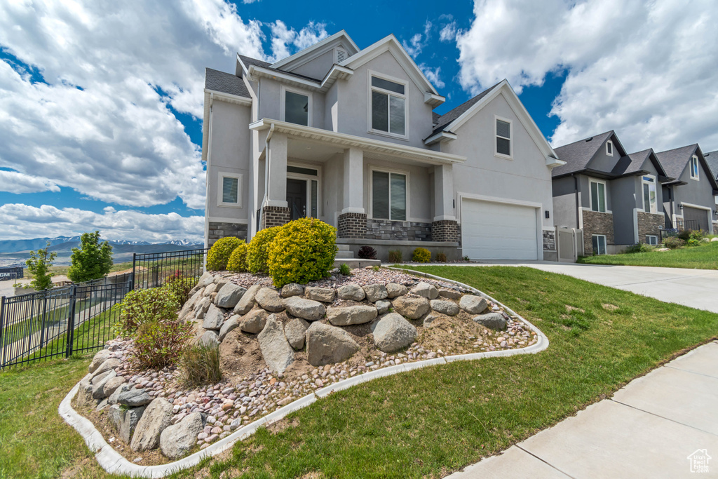 Craftsman house featuring stucco siding, stone siding, concrete driveway, an attached garage, and a residential view