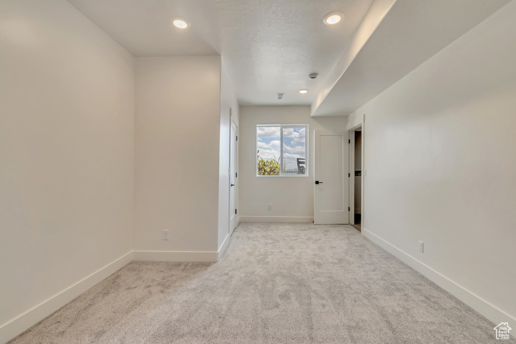 Spare room with light colored carpet, baseboards, and recessed lighting